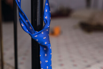 Corbata azul de atuendo de novio colgada en una cama preparada 