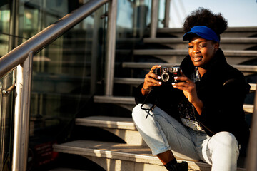 Young female traveler with camera. Beautiful african woman traveling around the city