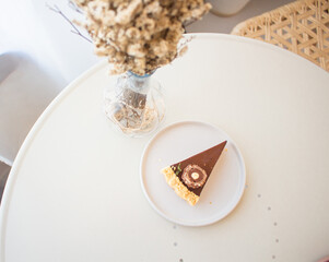 Top view of Chocolate Cheesecake with dried flowers on white table.