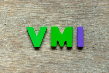 Color alphabet letter in word VMI (abbreviation of vendor managed inventory) on wood background