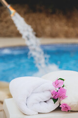 Obraz na płótnie Canvas White towel with pink flowers near the spa pool in the hotel on vacation. High quality photo