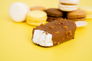 Vanilla Ice Cream with Chocolate on a Stick on a yellow background. Blurred sweets in the background