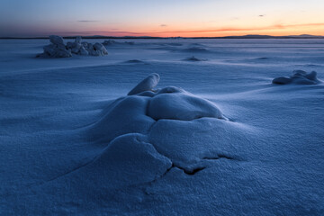 Ice hummocks piling up on the shore of the Kandalaksha Bay of the White Sea at sunset.