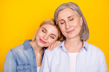 Photo portrait of dreamy daughter and mother smiling spending free time together isolated vibrant yellow color background