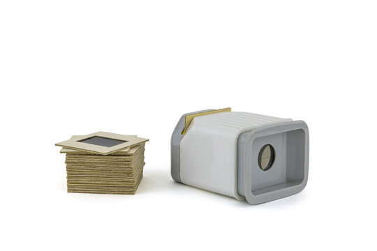 Vintage Soviet device for viewing film photographs Diascope and a stack of slides next to it. Isolated on white.