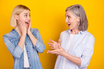 Photo portrait of mother and amazed daughter talking to each other smiling isolated vivid yellow...
