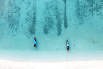 Top view or aerial view of long tail boats on the blue sea with white beach.