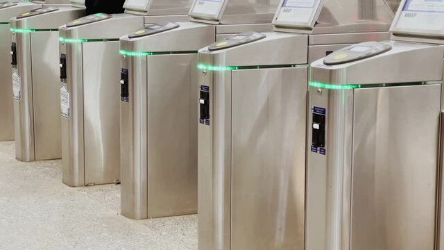 Passengers put subscription cards to contactless payment terminals on an entrance to metro station, barriers, nfc system reader