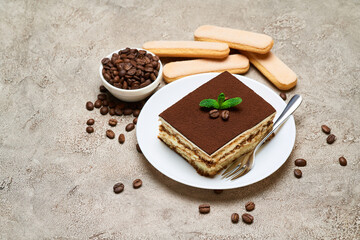 Portion of Traditional Italian Tiramisu dessert and coffee beans on grey concrete background