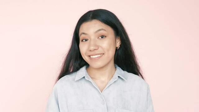 A smiling young hispanic woman  nodding positively to the camera standing isolated over pink background, nod in agreement, give positive reply with satisfied smile, talking, agree, pink background