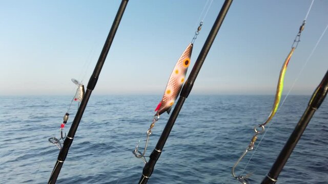 Three fishing rods hooked up with spinners, ready for fishing. The rods are lined up in a row on a small fishing boat. It is a beautiful sunny spring day. 1080p