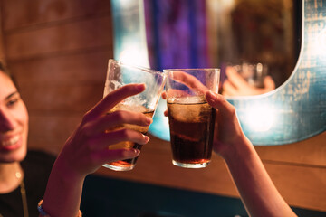 Dos chicas en un bar brindando con refresco