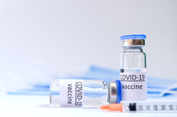 Creative ideas of vaccination concept. Top view of medical masks and vaccine vial glass bottles for vaccination against COVID-19. Coronavirus pandemic. Copy space. 