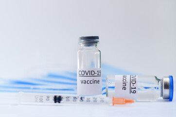Creative ideas of vaccination concept. Top view of syringe with medical masks and vaccine vial glass bottles for vaccination against COVID-19. Coronavirus pandemic. Copy space. 