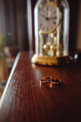 Two gold wedding rings on a dark wooden table.