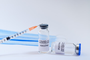 Creative ideas of vaccination concept. Top view of syringe with medical masks and vaccine vial...