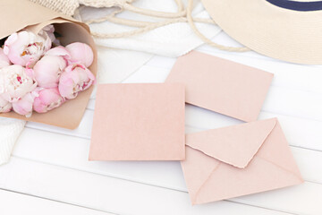 Wedding greeting card concept. Top view mockup on wooden background with peonies flowers. Flat lay style in light colors.