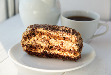 Chocolate cake on the white plate and cup of tea