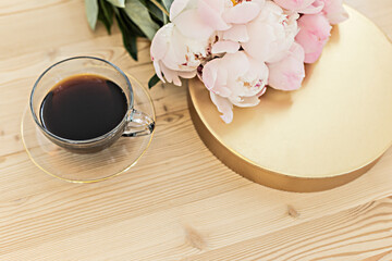 Styled composition with pink tulips and cup coffee on gold background. Flat lay floral frame and white textile. Border top view.