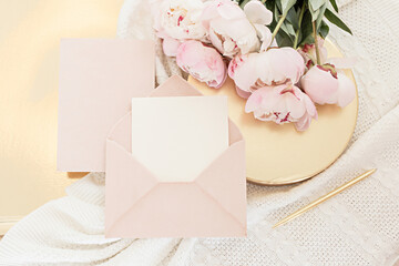 Wedding greeting card concept. Top view mockup on wooden background with peonies flowers. Flat lay style in light colors.