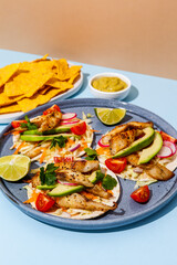 Tacos with crispy fish, avocado, guacamole sauce, nachos chips and lime. Mexican cuisine
- 427885636