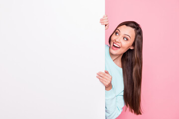 Photo of pretty surprised young woman look stand behind blank white board empty space isolated on shine pink color background