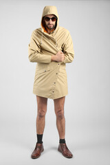Exhibitionist in beige coat on light background