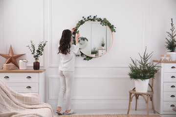 Woman decorating mirror with eucalyptus branches at home