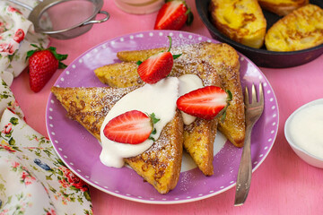Sweet French toasts served with whipped cream and strawberries