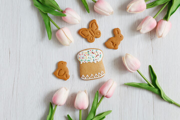 Homemade Gingerbreads in the form of egg, cake, candle on Easter with pink tulips on wooden background. Space for text