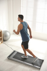 Fototapeta premium Sporty man training on walking treadmill at home