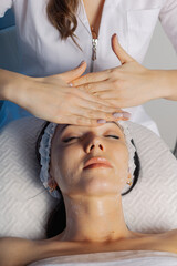 Naklejka premium Professional beautician woman massaging face to client.