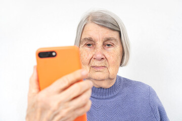 Aged elderly woman with wrinkled face using smartphone.