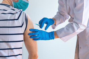 Female doctor applying a vaccine on a male patient .