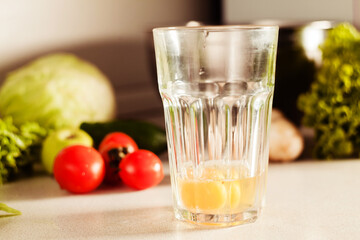 Cooking an omelet in the kitchen. On the countertop is a glass of broken eggs. Vegetables and herbs are laid out nearby