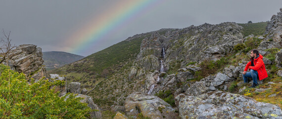 Naklejka premium panorama of a waterfall with a rainbow in the sky and green pastures and rocks