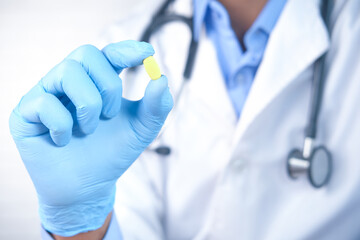 doctor hand in latex gloves holding medical pill close up 