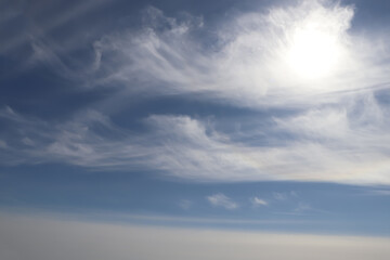 Bright sun and fluffy white clouds in blue sky