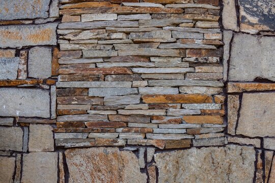 Fototapeta Brown beige grey bricks wall as abstract colorful material pattern. Architectural ornaments background, rocks and stones arranged in rows. Color combination of warm orange gamma of pastel ground tones