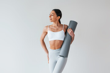 With yoga mat. Woman with sportive slim body type in underwear that is in the studio