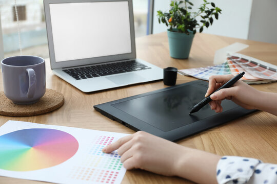 Professional designer with graphic tablet at wooden table, closeup