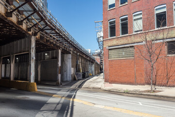 Curving road alongside elevated railroad tracks in industrial area of urban Chicago