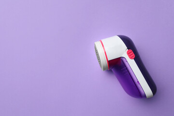 Modern fabric shaver to remove lint on purple background, top view. Space for text