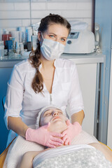 Professional beautician makes a facial massage to a woman.