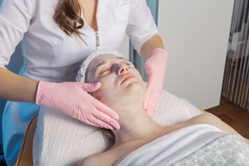 Obraz na płótnie Canvas Professional beautician makes a facial massage to a woman.