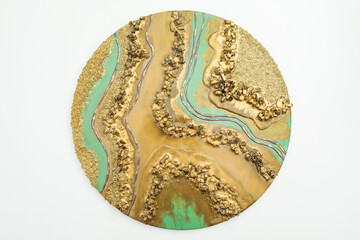 Round resin art artwork with golden colors and glass.