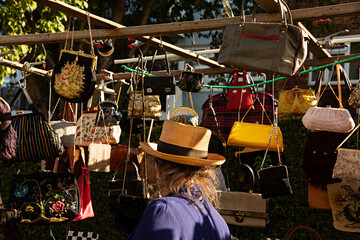 Mujer de compras en mercadillo mirando bolsos.