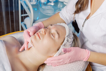 Fototapeta na wymiar Professional beautician wipes a woman's face after the procedure.