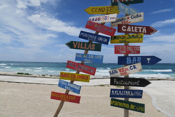 Colorful wooden trail sign at the beach in the sand, at a sunny day at the ocean, it shows you the...
