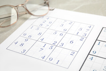 Sudoku and eyeglasses on table, closeup view